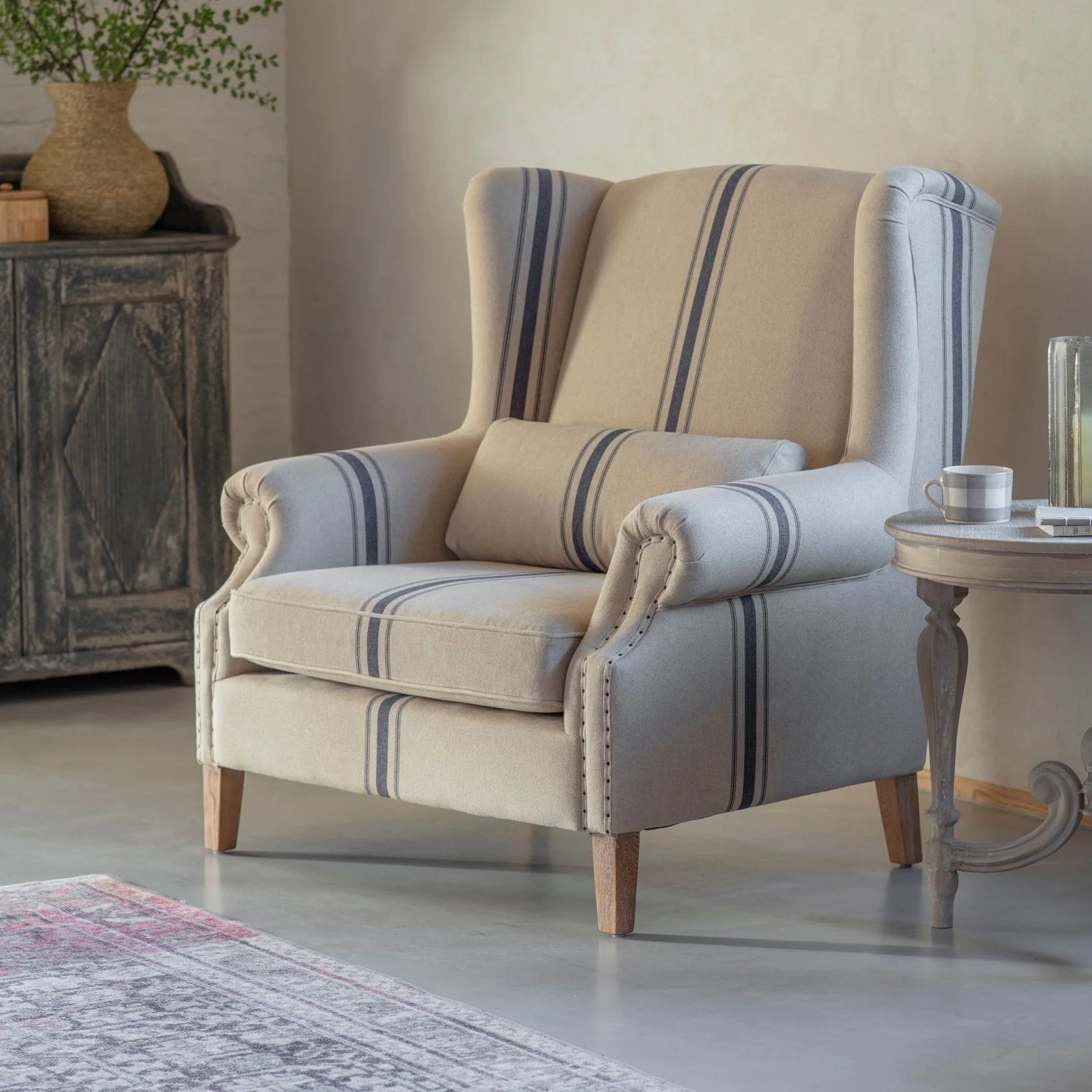 Beige and blue striped armchair in a room with a side table and decorative items.