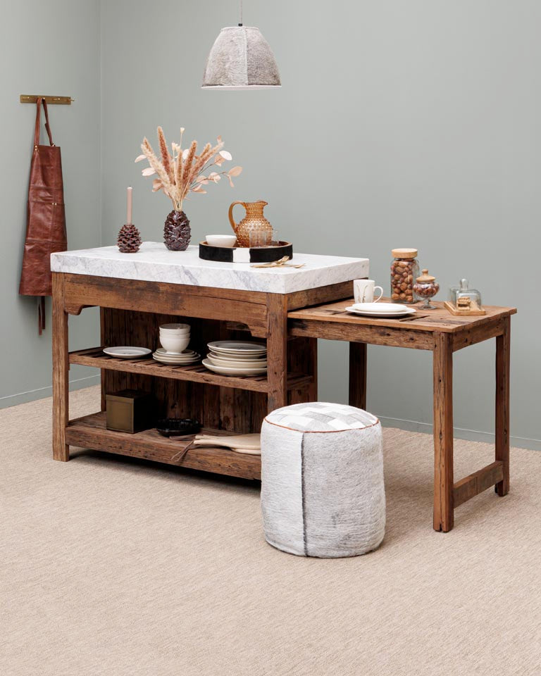 Wooden kitchen island with marble countertop and decorative items against a gray wall.