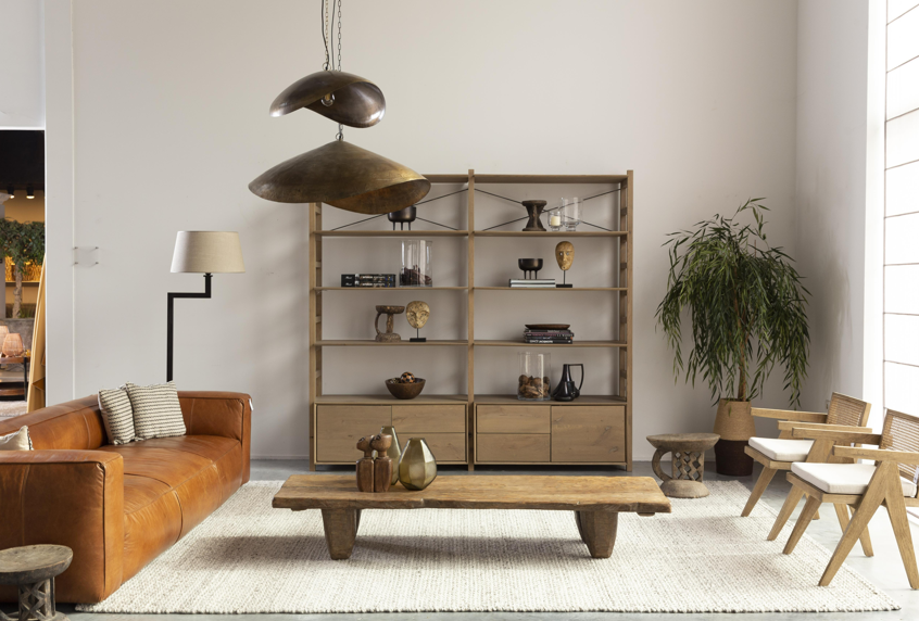 Modern living room with brown leather sofa, wooden coffee table, and bookshelf.