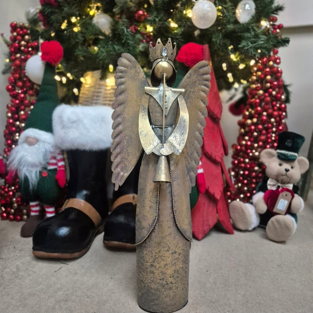 Decorative angel figure with boots in front of a Christmas tree and ornaments.