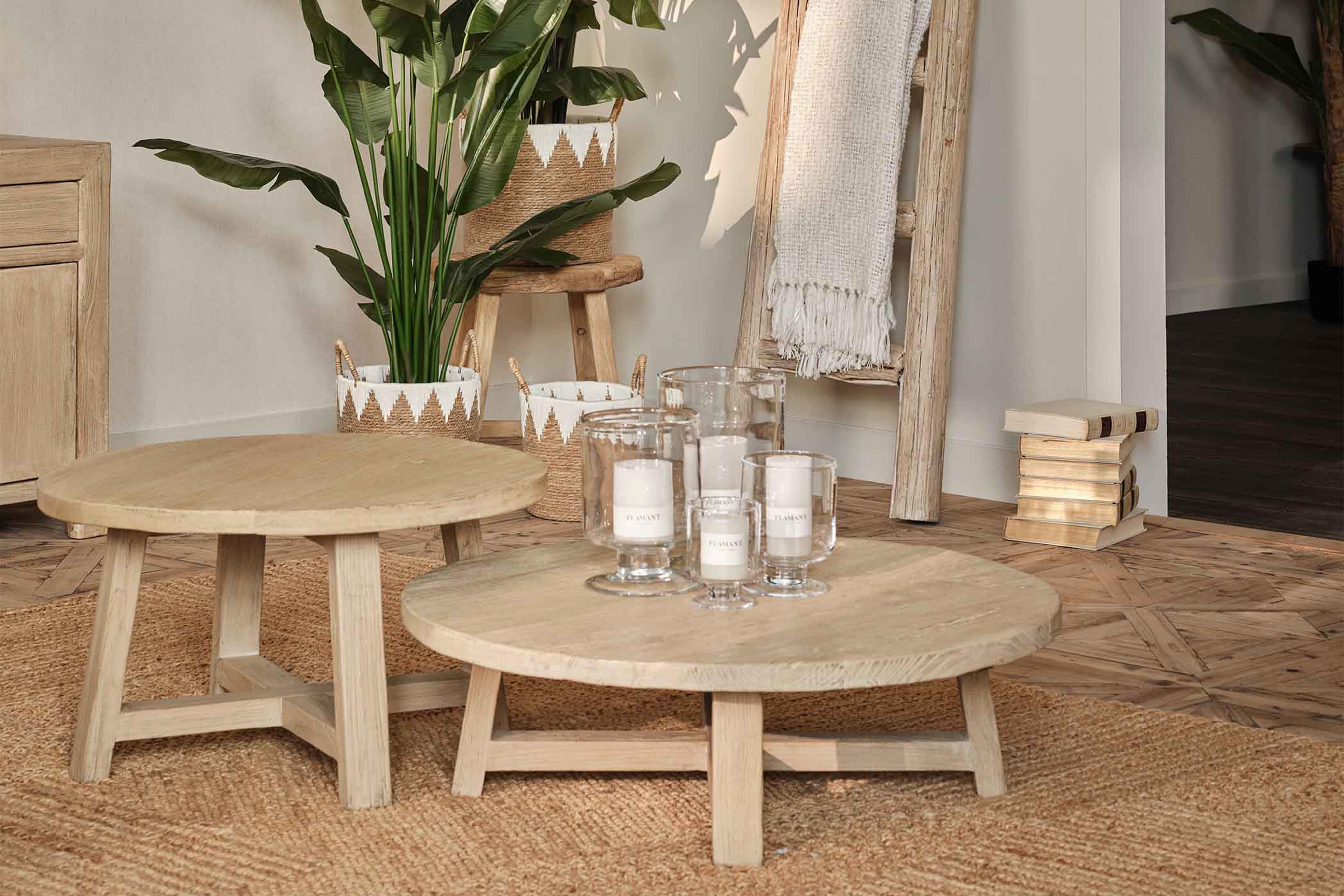 Round wooden coffee table with decorative items in a room setting.