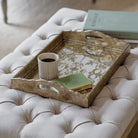Decorative tray with a cup and book on a cushioned surface