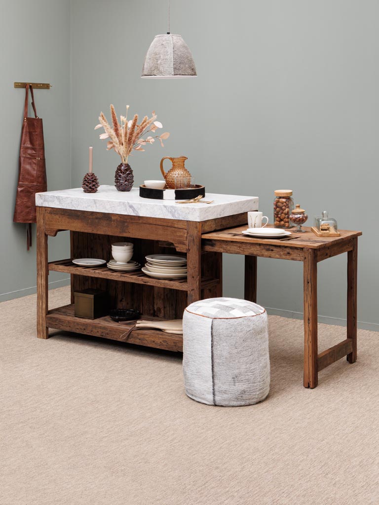 Wooden kitchen island with marble countertop and decorative items against a gray wall.