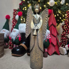 Decorative angel figurine in front of a Christmas tree with ornaments.